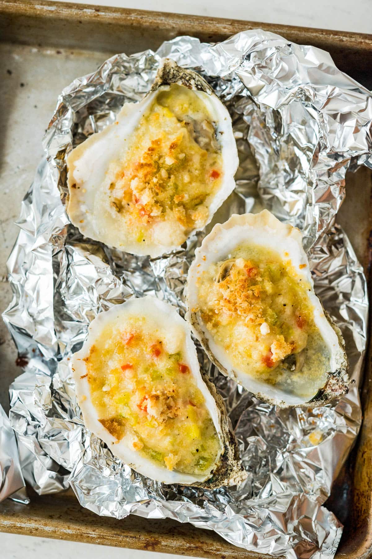 Baked oysters on a crumpled piece of foil.