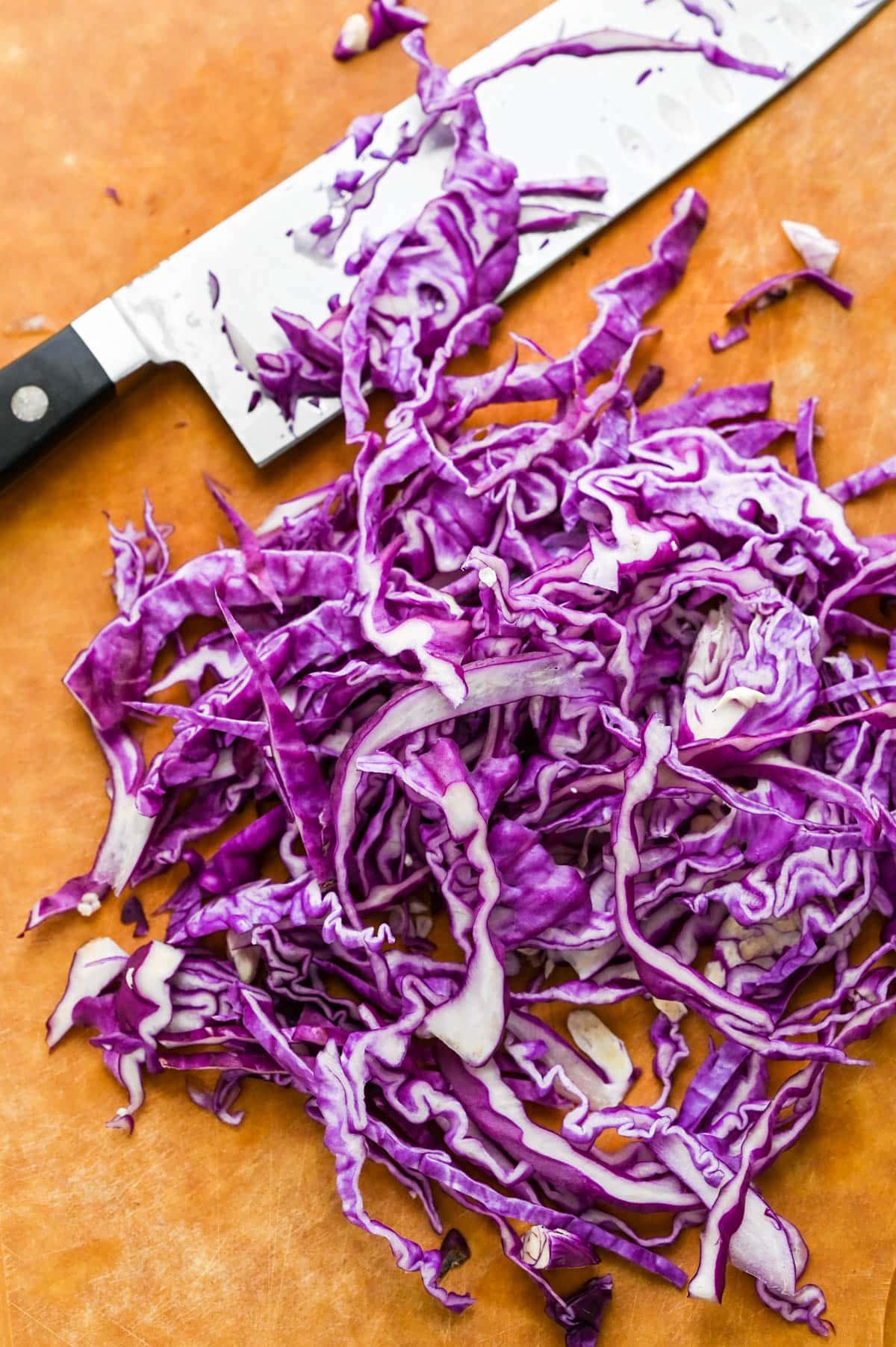 Slicing the red cabbage thinly with a santoku knife.