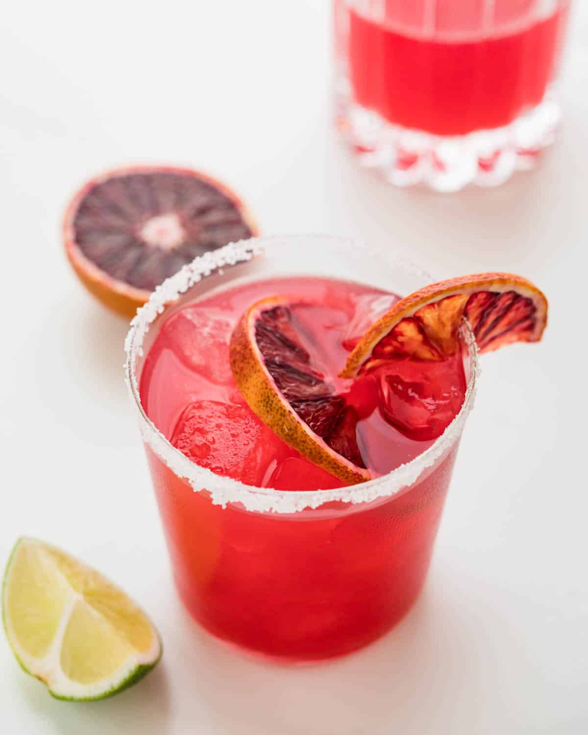 a blood orange margarita with slices of blood orange and lime.
