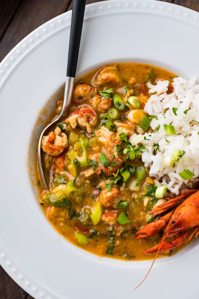 A close-up photo of the etouffee recipe in the bowl with a scoop of white rice and a whole crawdad tucked into the bowl.