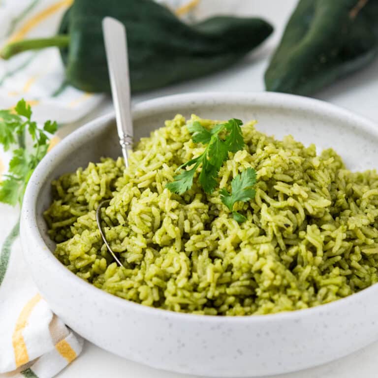 arroz verde in a white bowl with a cilantro garnish.