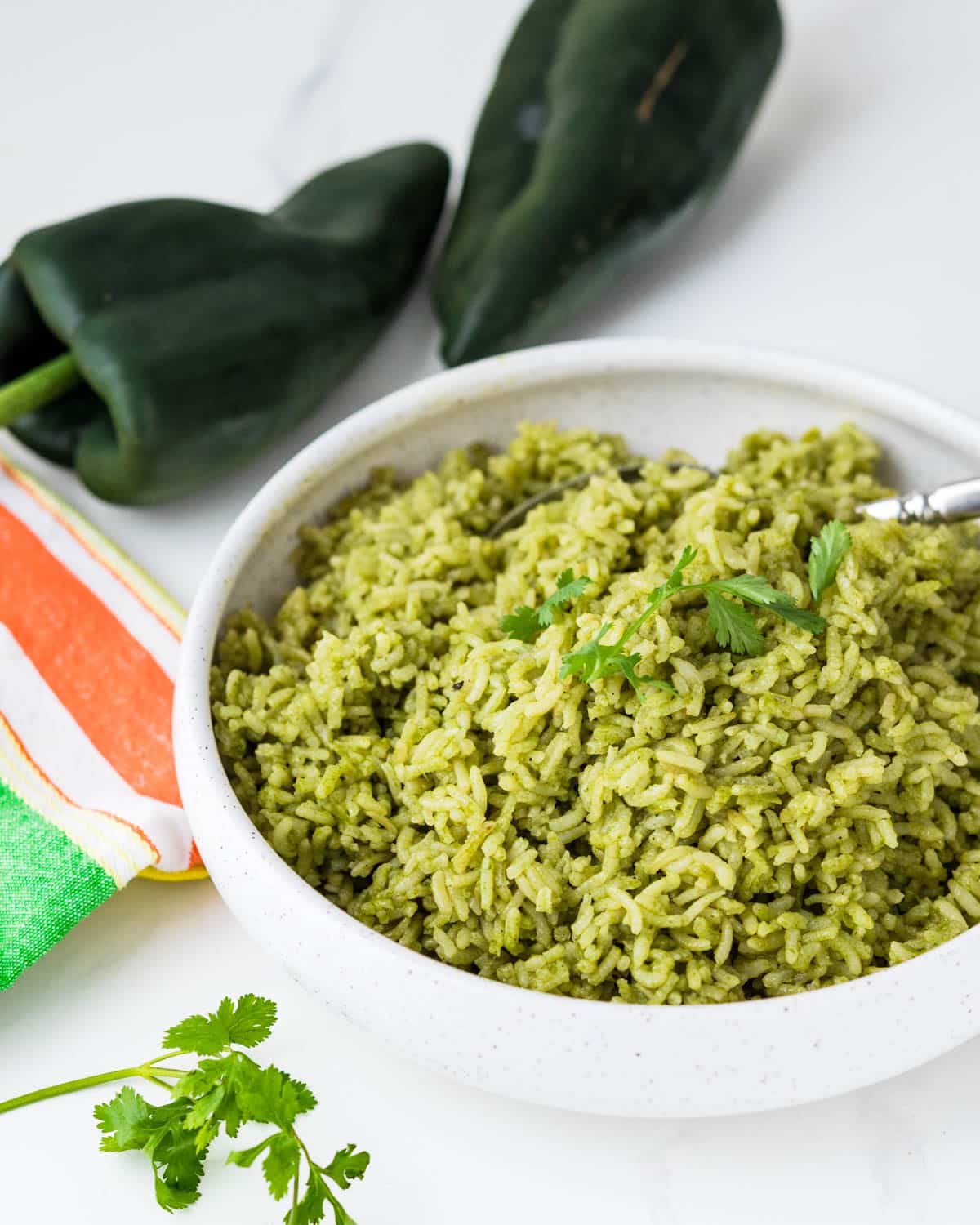 A bowl of Mexican green rice with a sprig of cilantro for garnish.