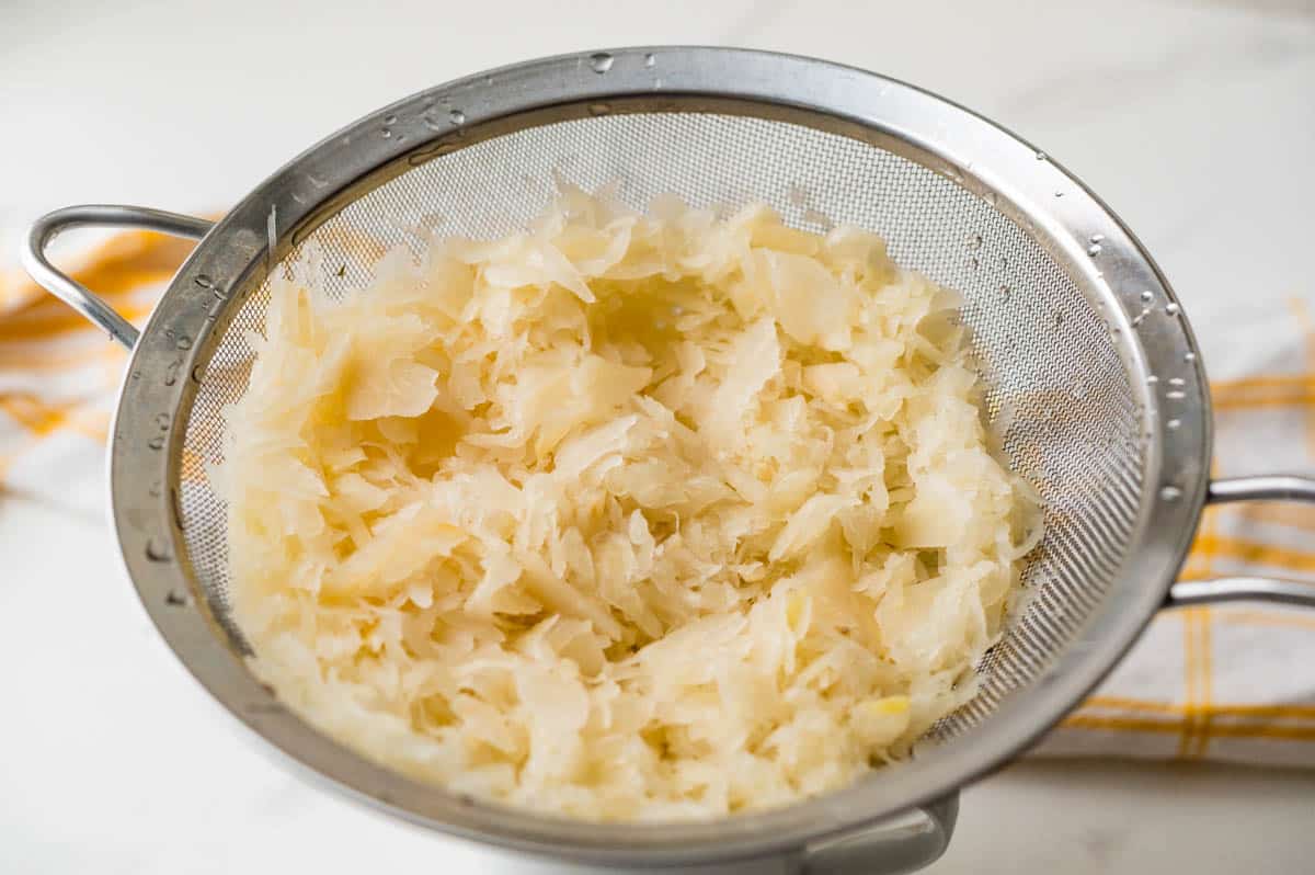 Rinsing sauerkraut in a fine mesh sieve under cold running water and draining.