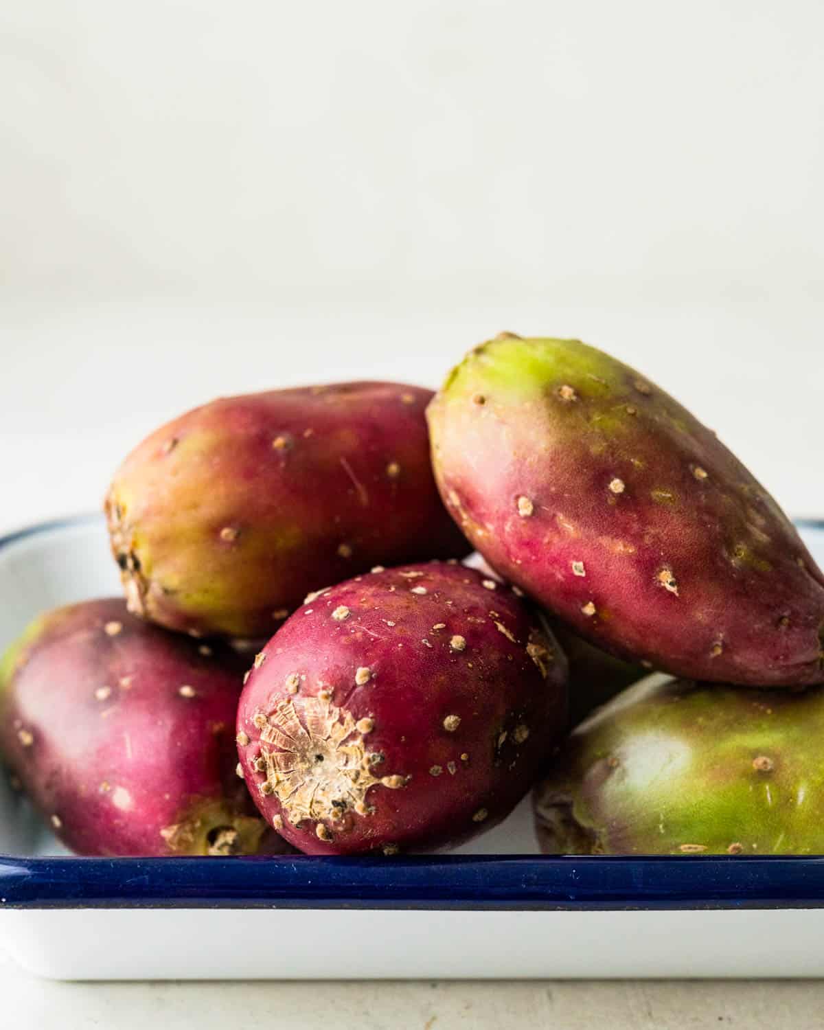 a pile of prickly pears on a blue and white platter.