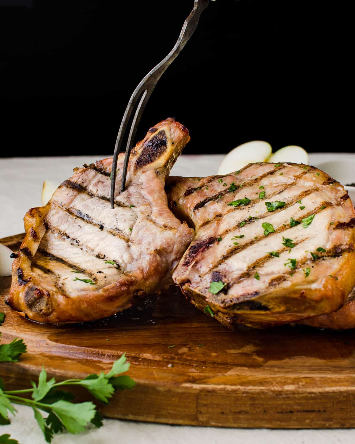 A cutting board piled with the best juicy, grilled pork chops ever.