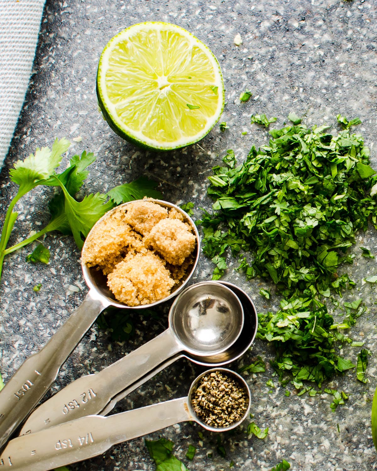 Brown sugar, cilantro, black pepper and lime juice on a cutting board.
