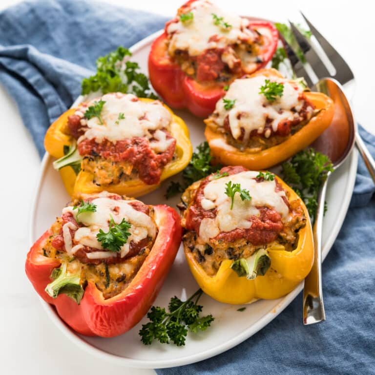 Chicken stuffed peppers on a white platter with a parsley garnish.