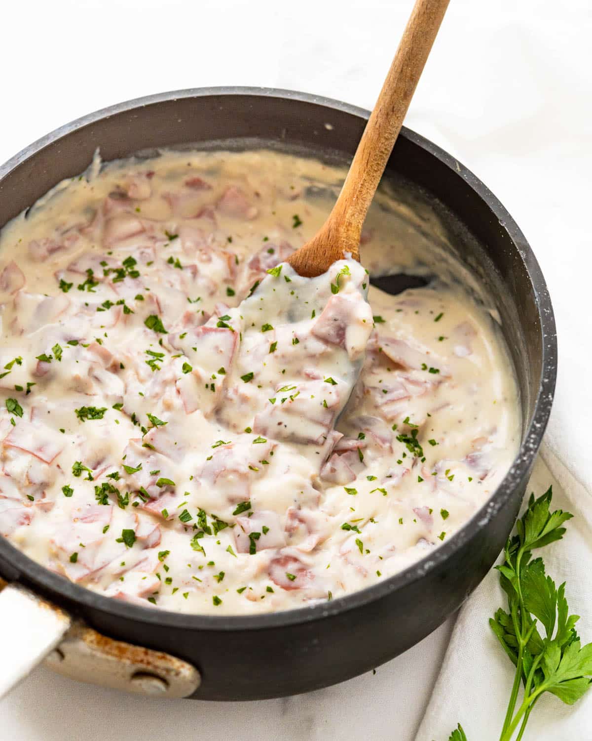 A skillet of creamed chipped beef garnished with parsley. 