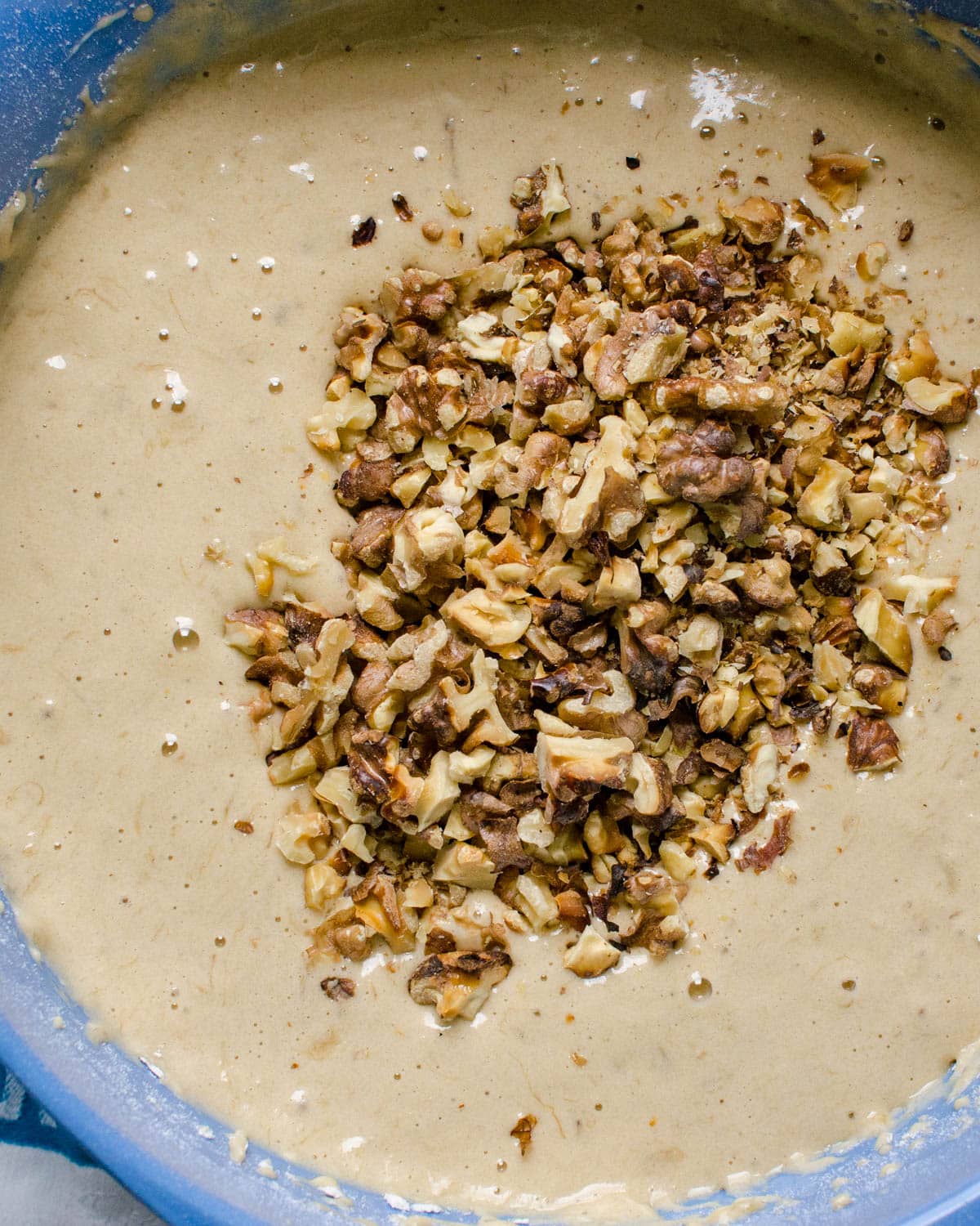 adding toasted walnuts to the banana bread batter.