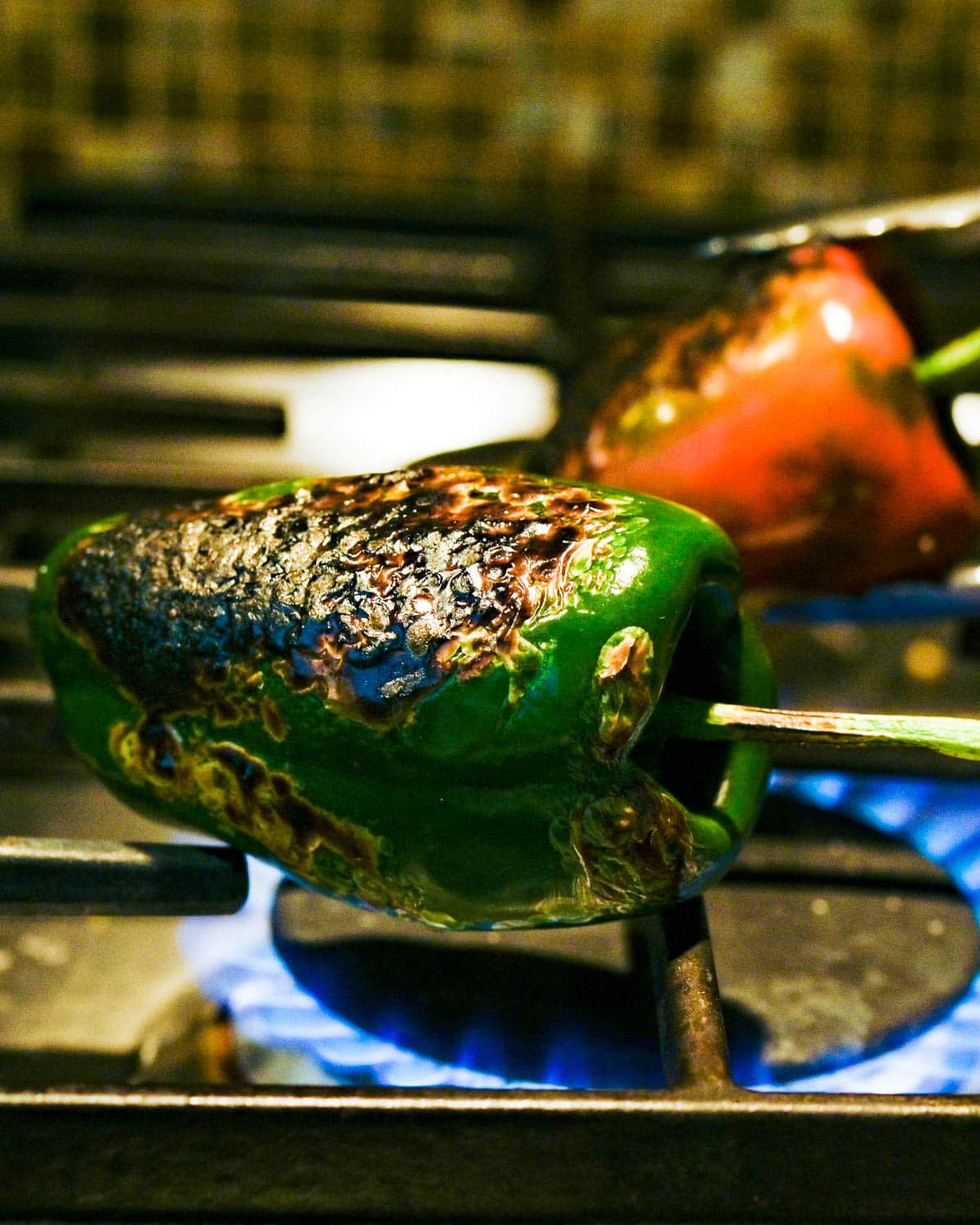 Roasting poblano peppers over an open flame on a gas stove.