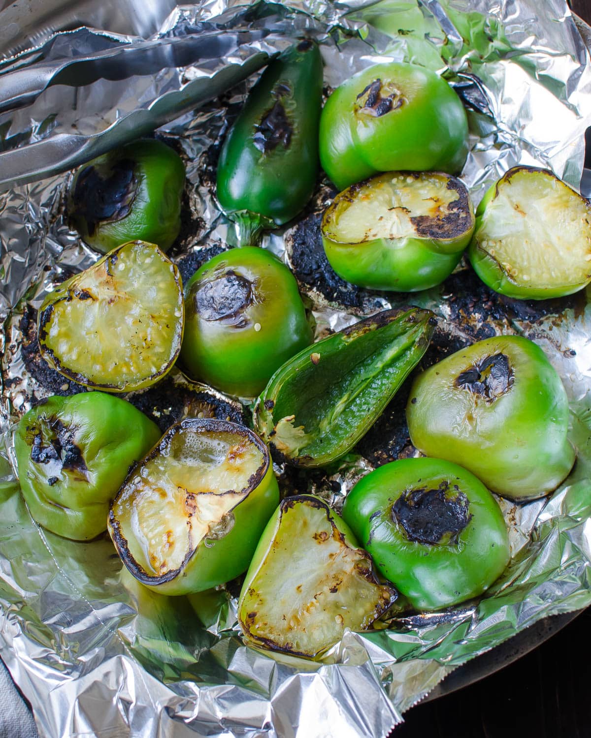Charring the tomatillos and jalapenos in a skillet lined with tin foil.