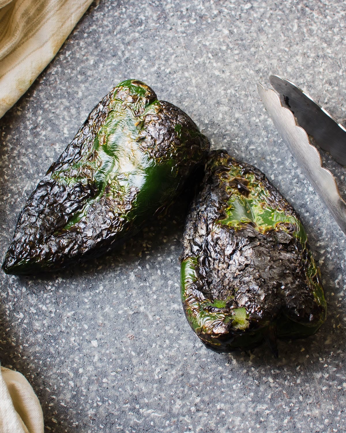 Charred poblano peppers on a cutting board.
