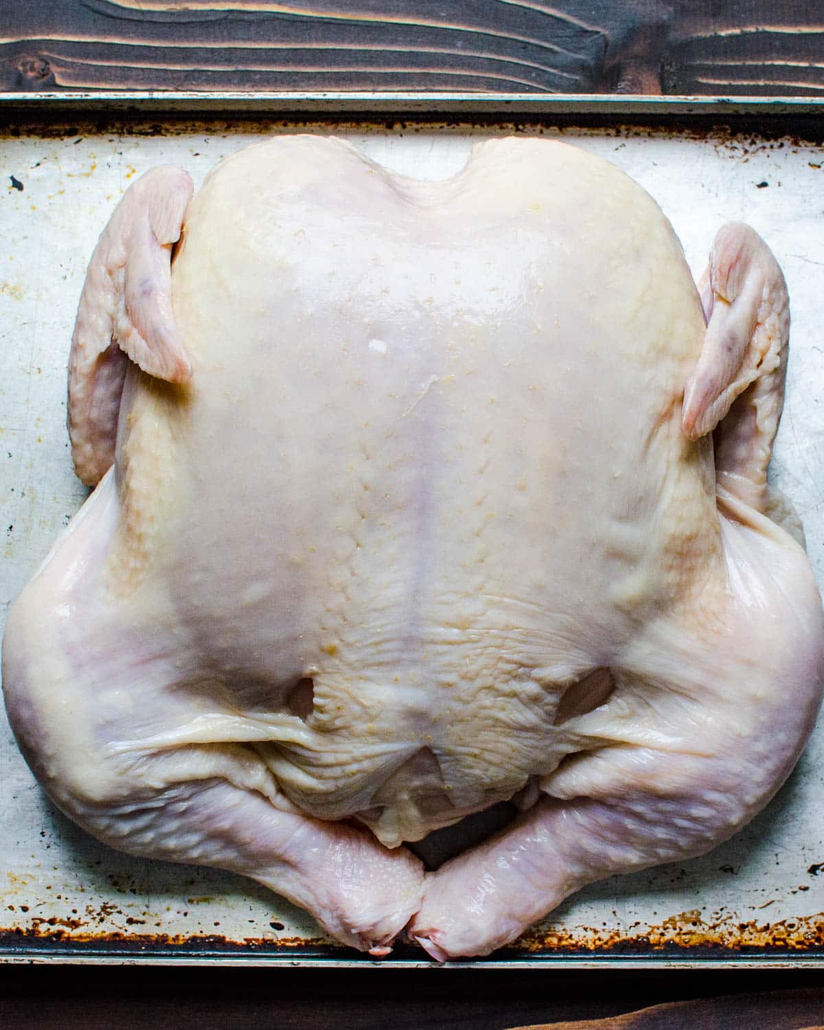a whole chicken on a baking sheet.