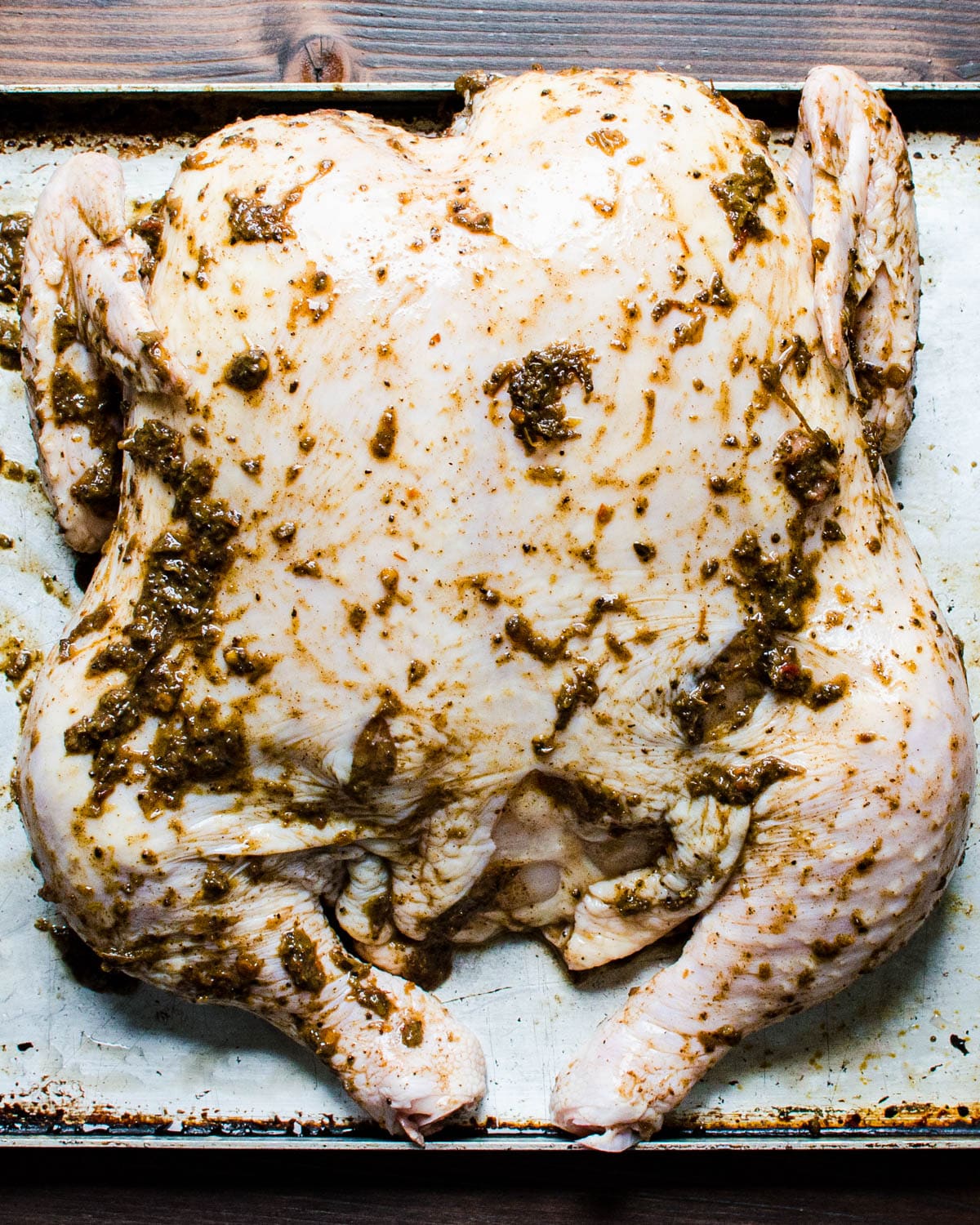Coating the spatchcock chicken with jerk seasoning.