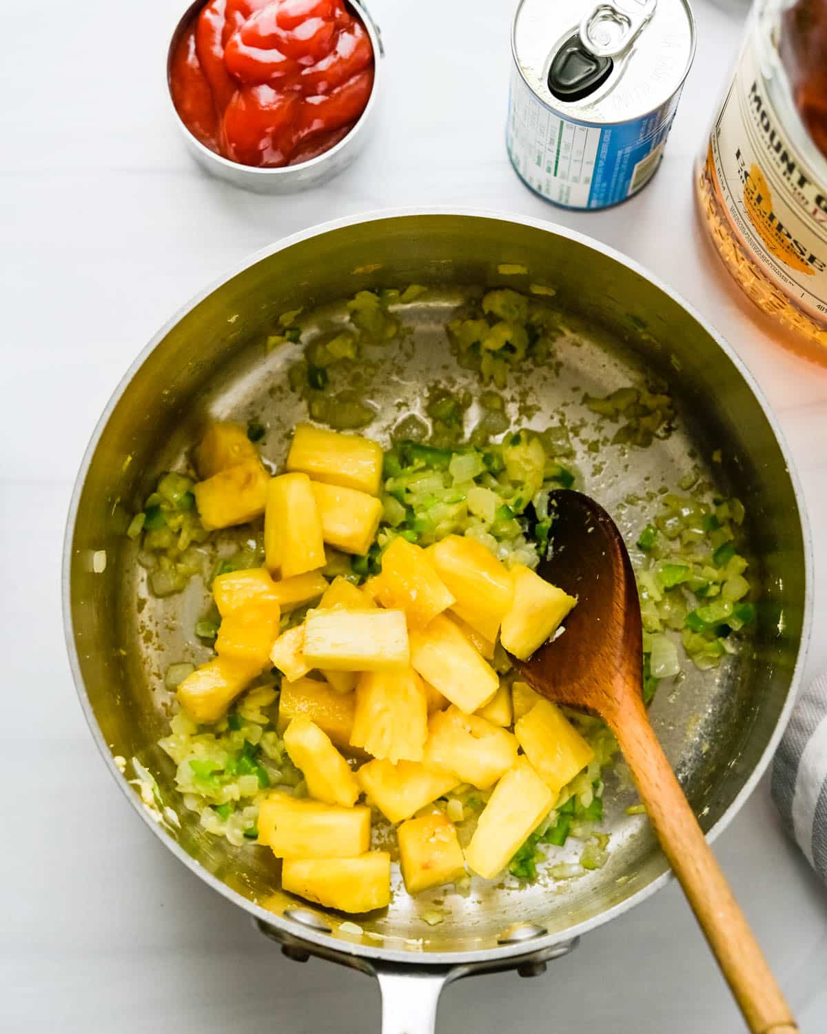 Adding pineapple chunks to the pan.