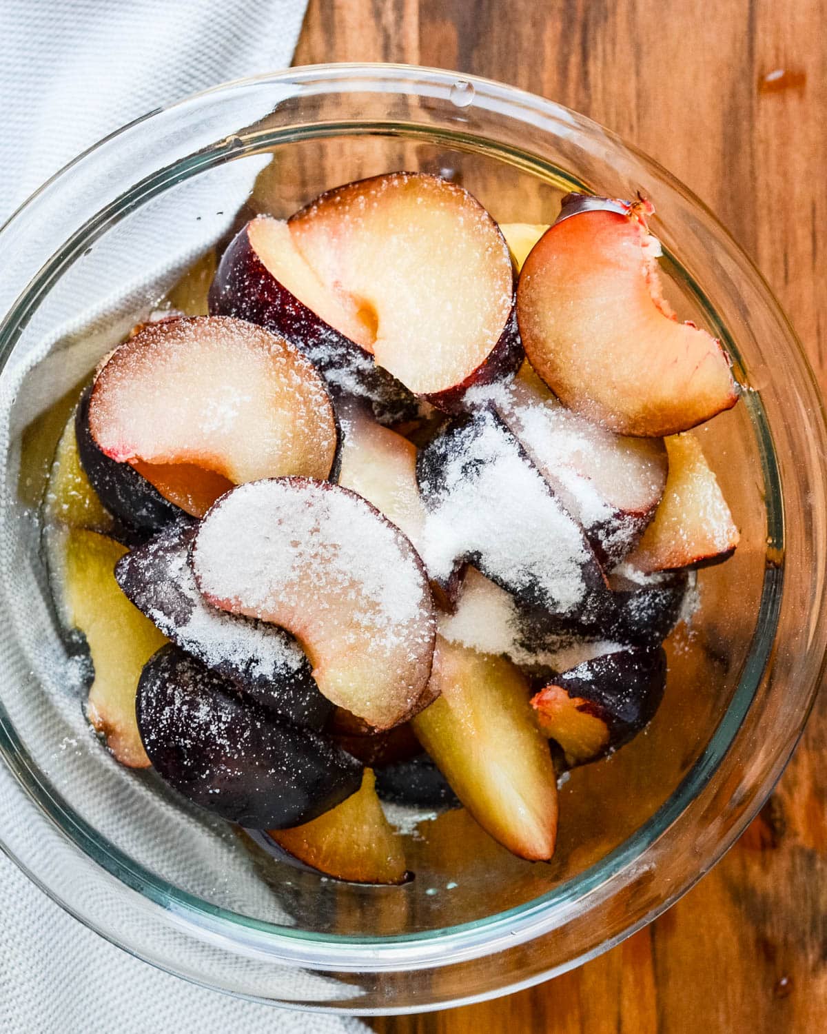 Adding sugar to the sliced plums.