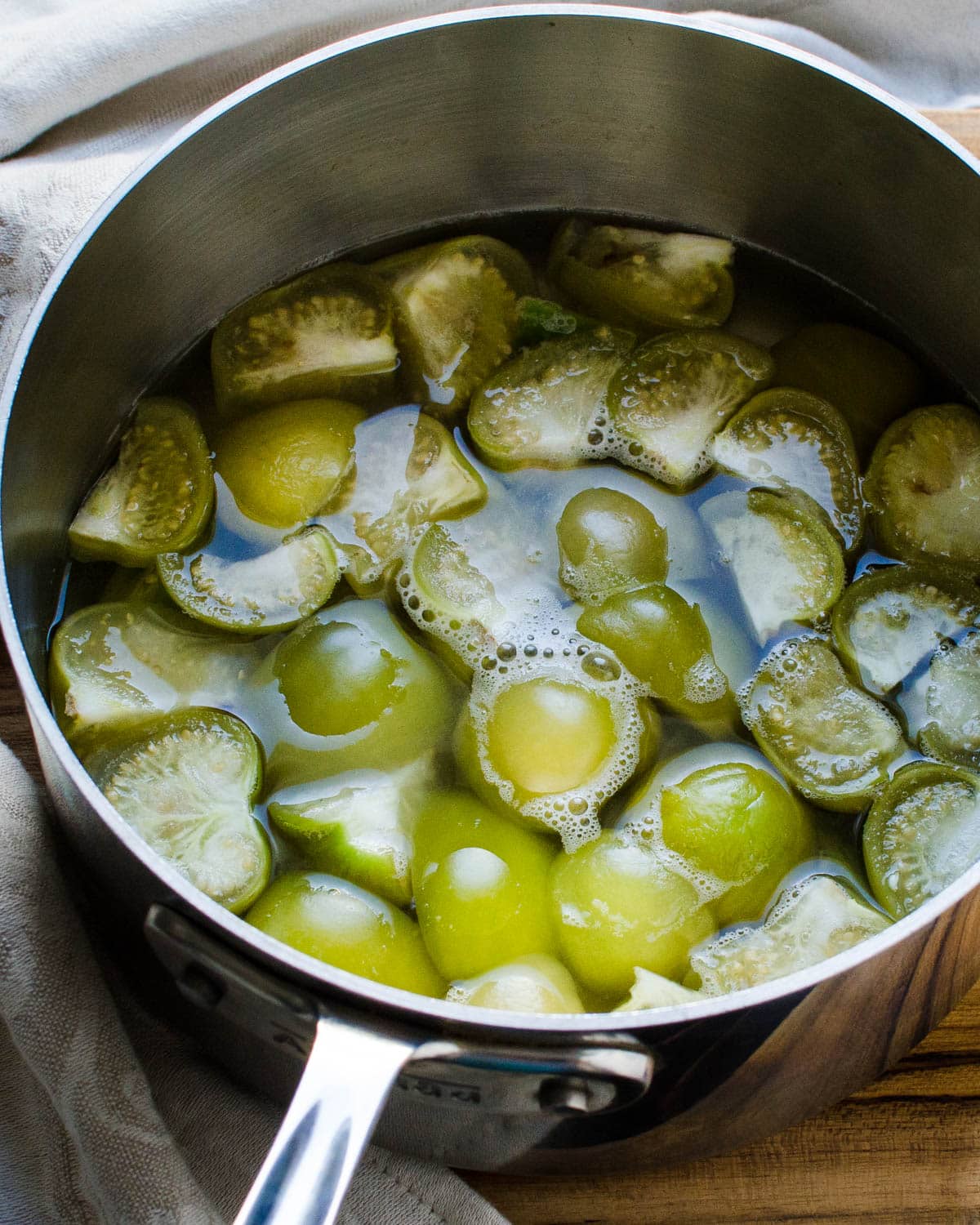 Cooked tomatillos and jalapenos in the saucepan.