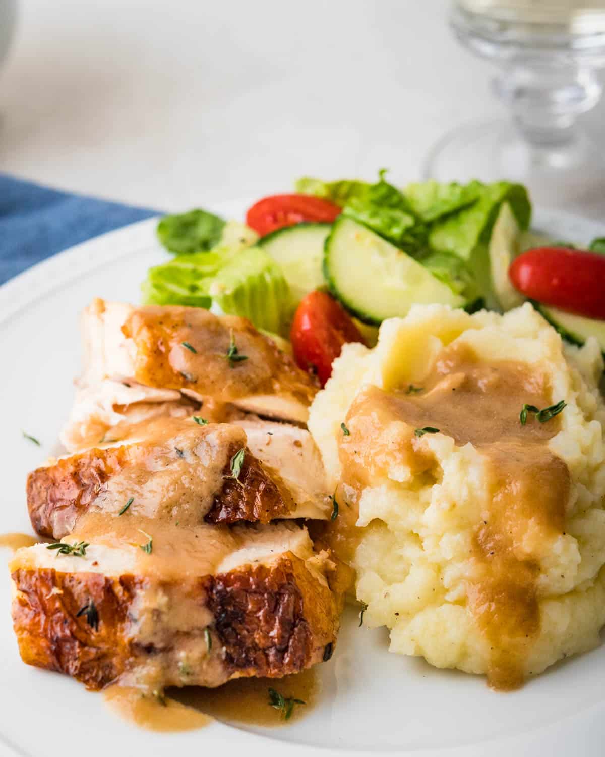 Three slices of chicken sauced with homemade gravy and a side of mashed potatoes.