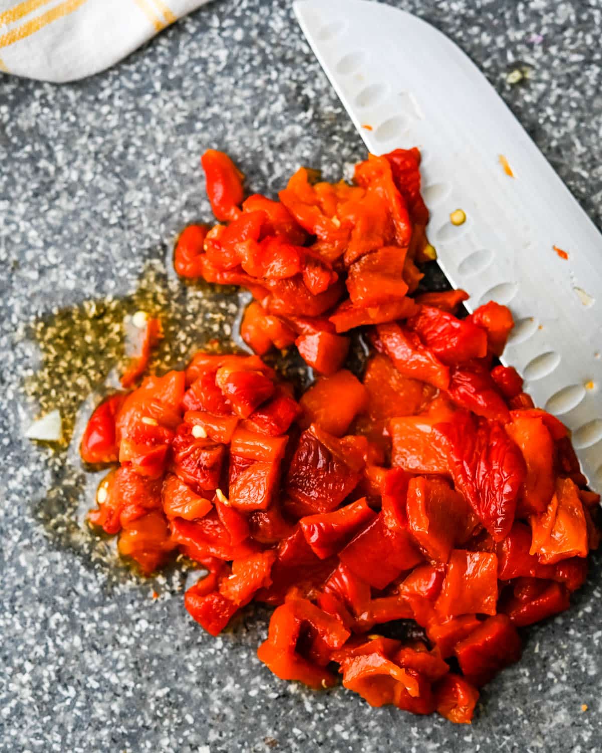 I am chopping roasted red peppers on a cutting board.