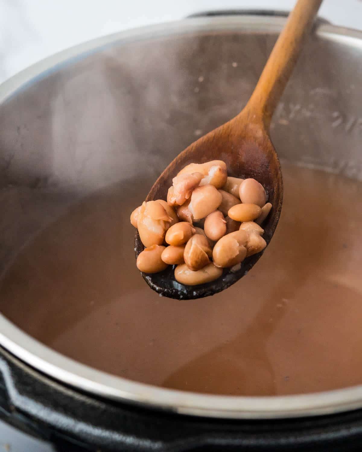 Par cook the pinto beans in a pressure cooker until tender.