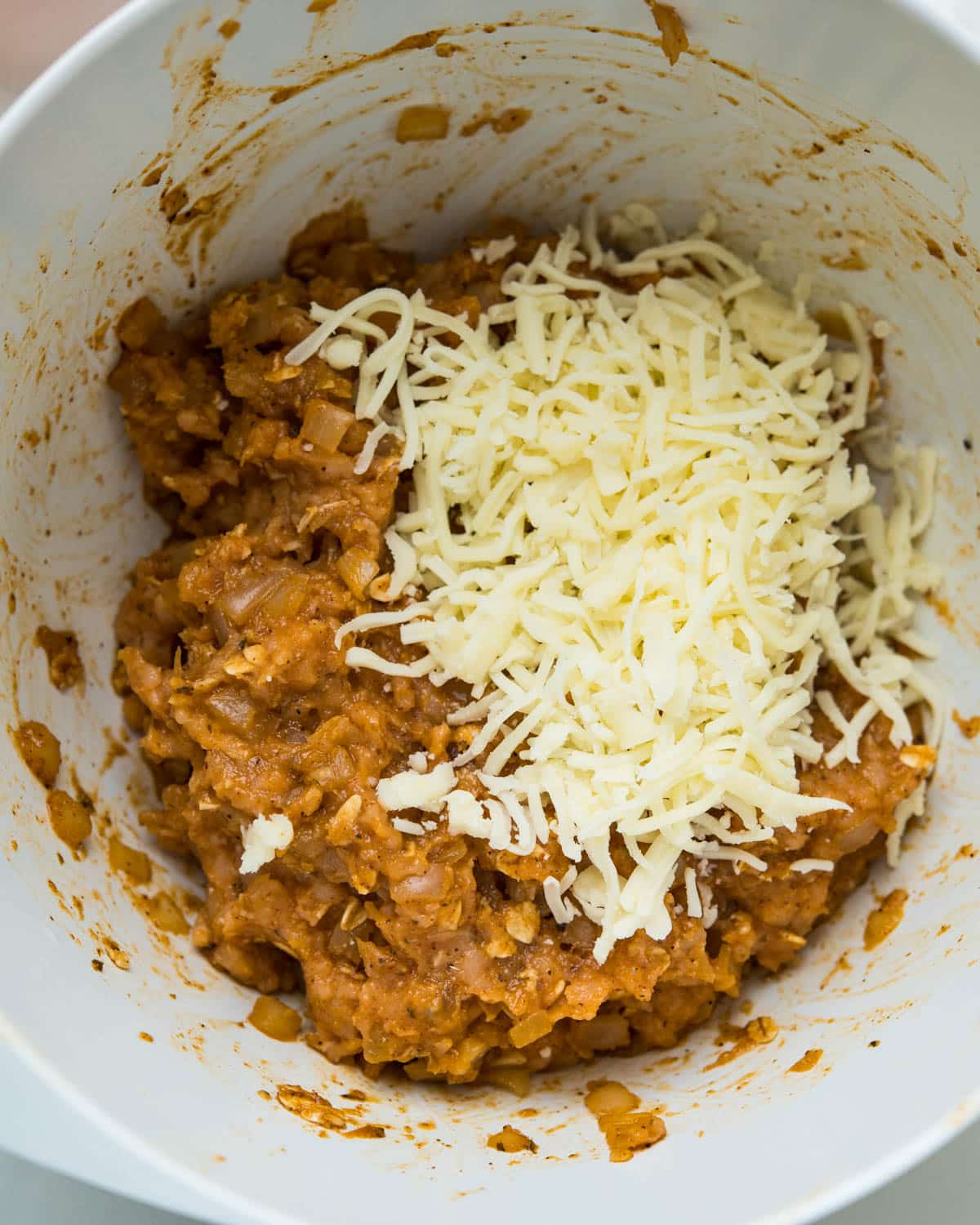 Adding ground turkey and half of the cheese to the taco filling mixture.