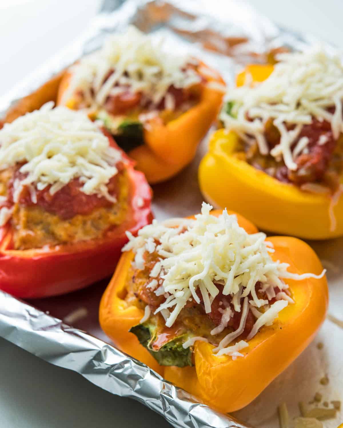 Adding salsa and cheese to the par-baked stuffed peppers.