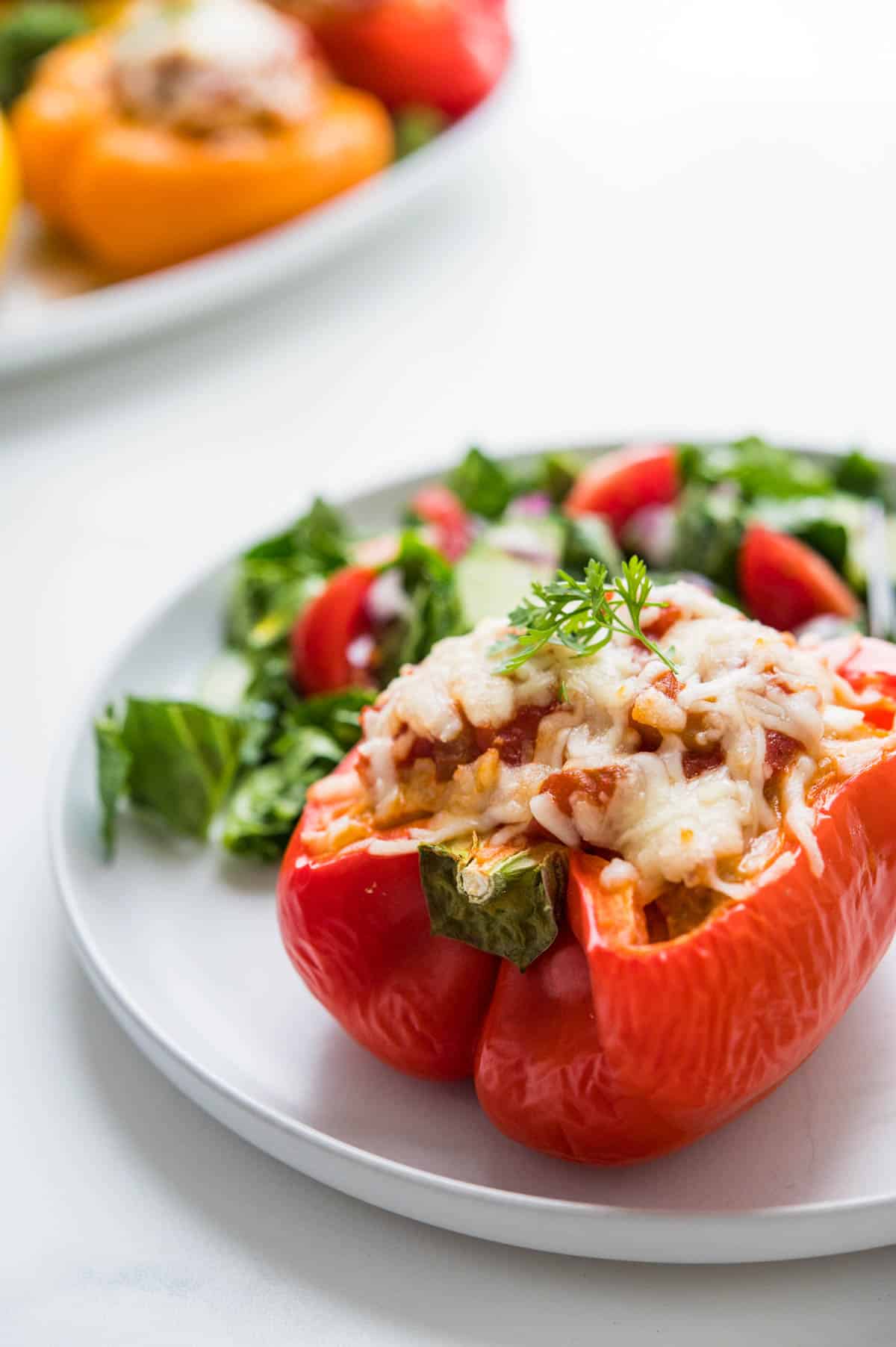A Mexican Stuffed pepper on a plate with a green salad.
