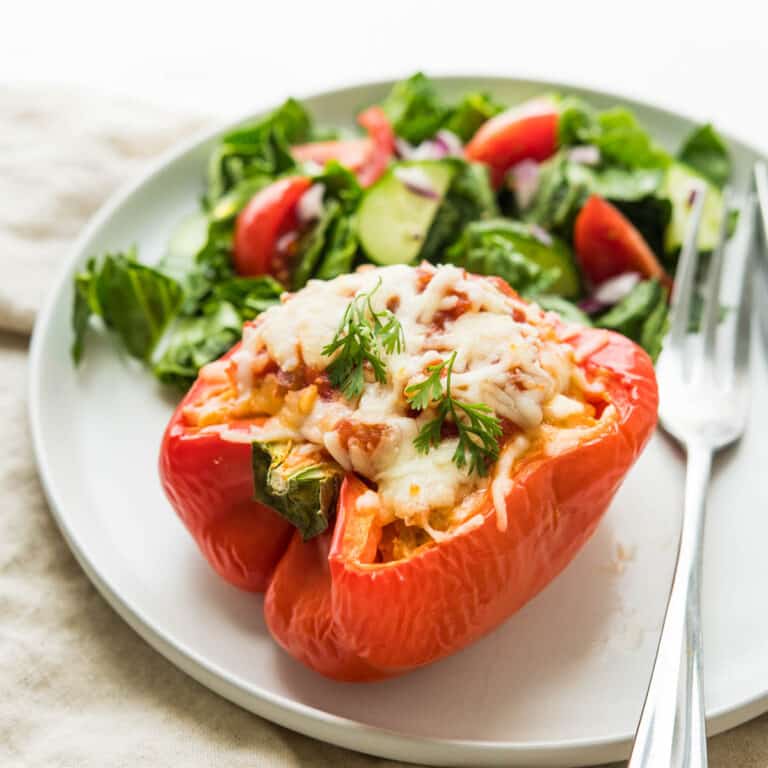 Taco stuffed peppers on a plate with green salad.