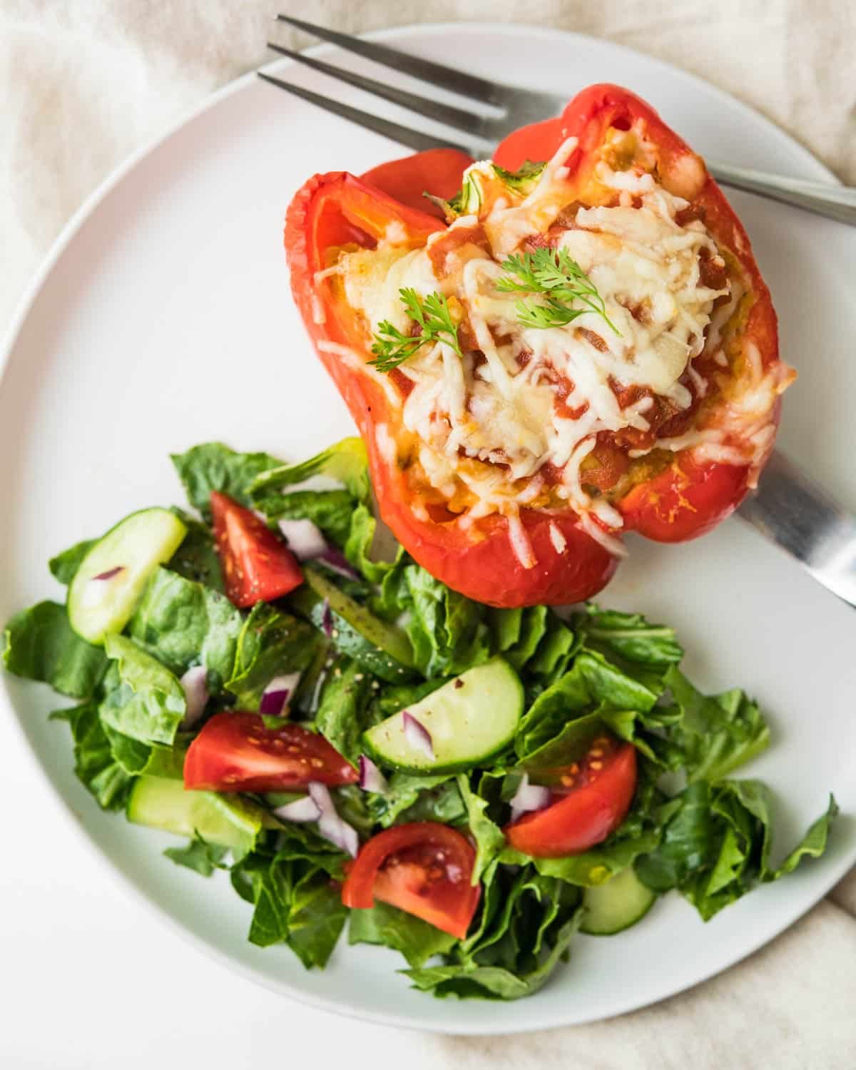 Stuffed red bell pepper with a side salad.