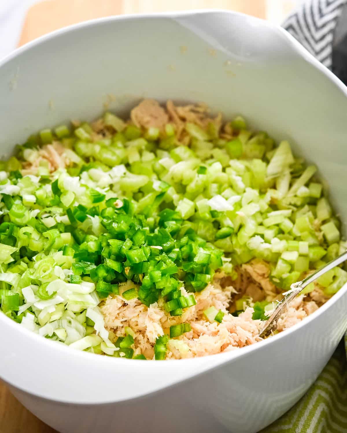 Adding fresh celery, onions and jalapenos to the flaked canned tuna.