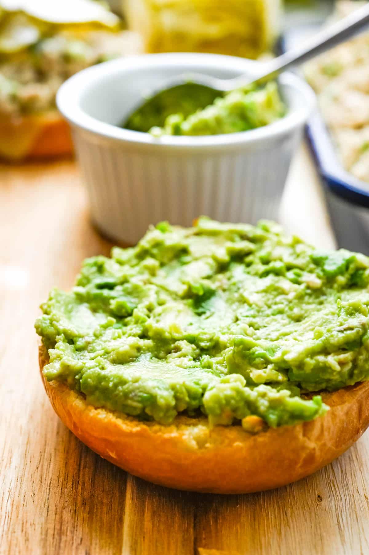 Spread the top bun with mashed avocado.