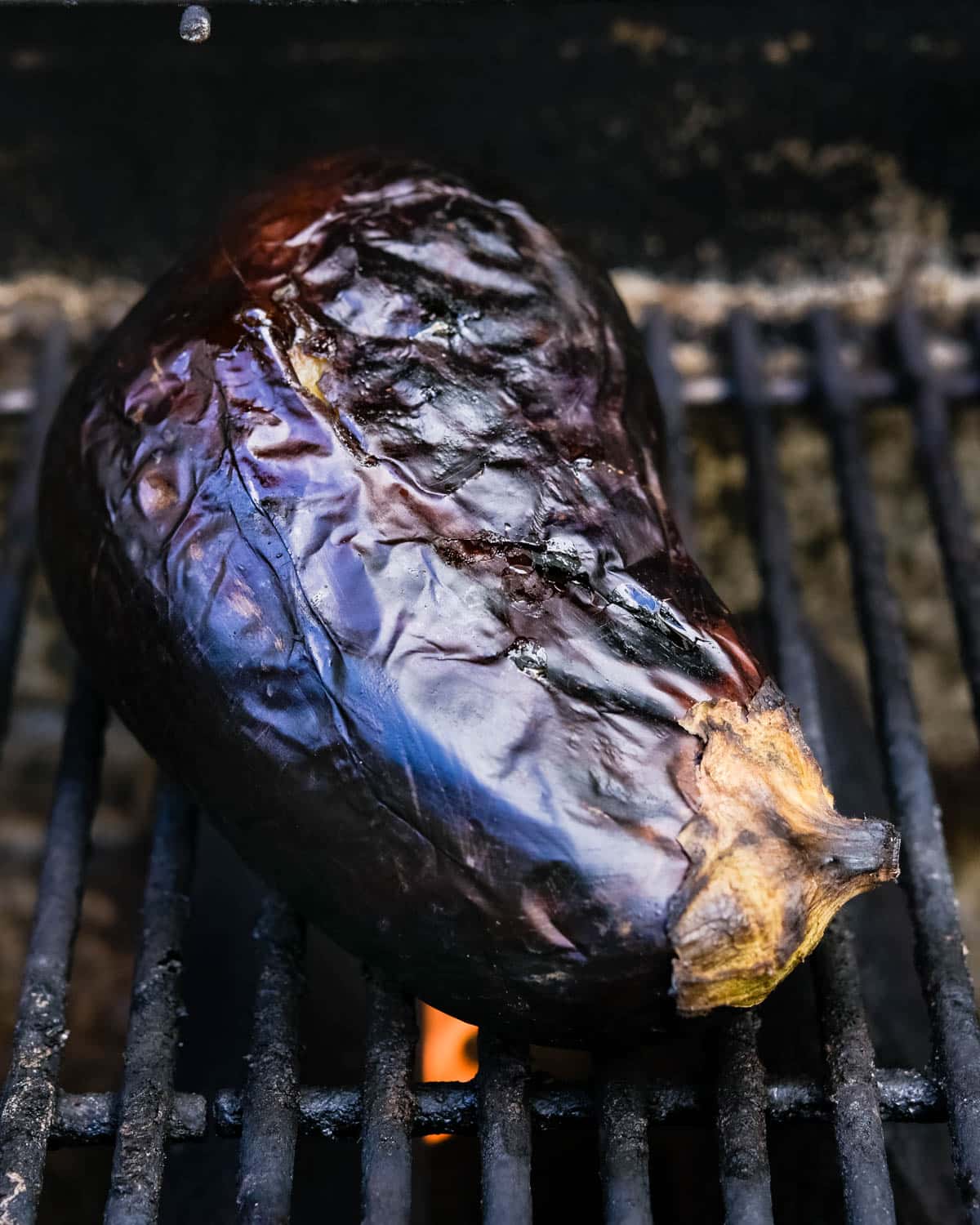 The wrinkled eggplant on the grill, shrinking as it cooks.