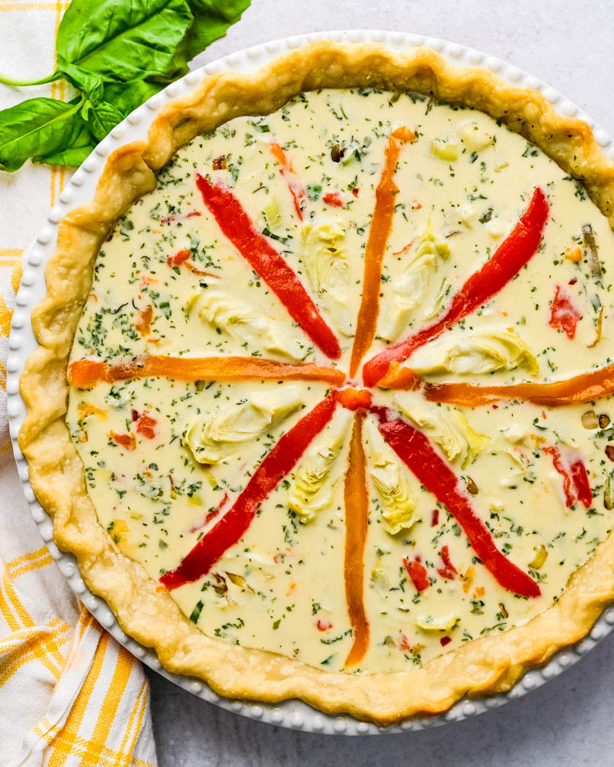Filling the pastry shell and arranging the vegetables on top of the quiche.