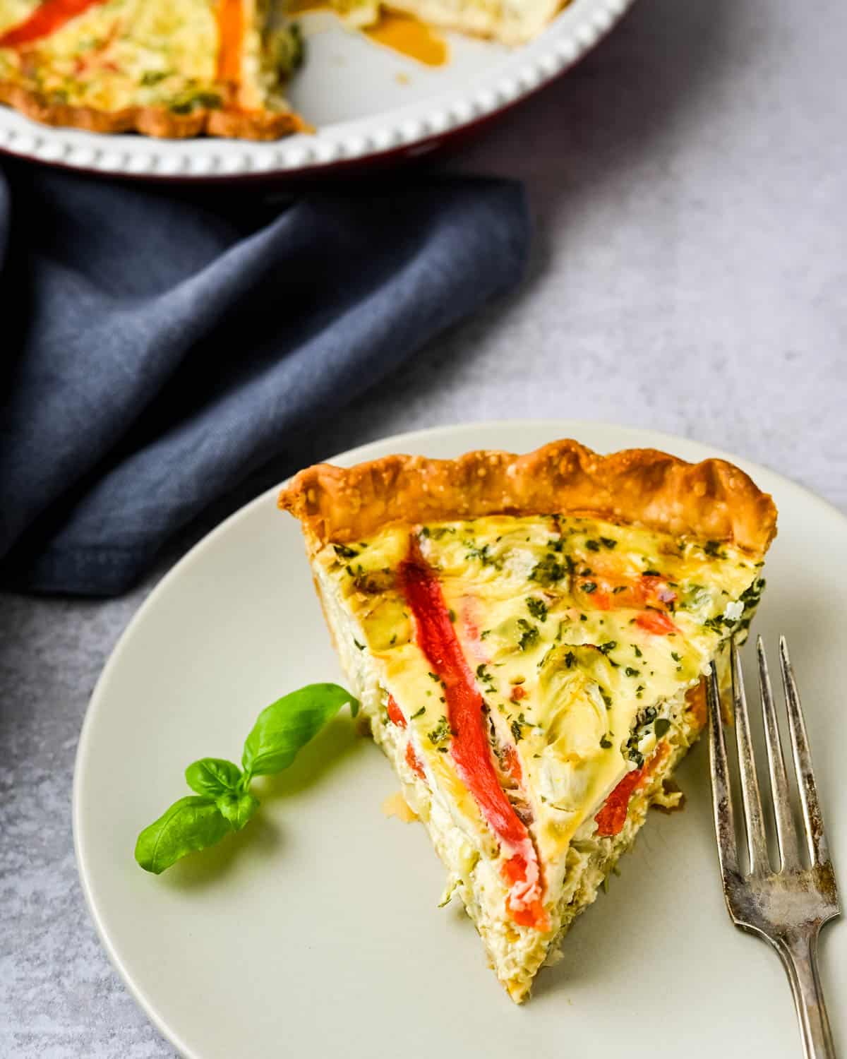 a slice of quiche on a plate.