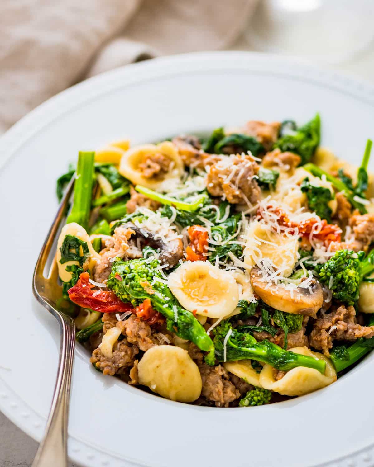 a bowl of broccoli rabe with sausage and orecchiette pasta.