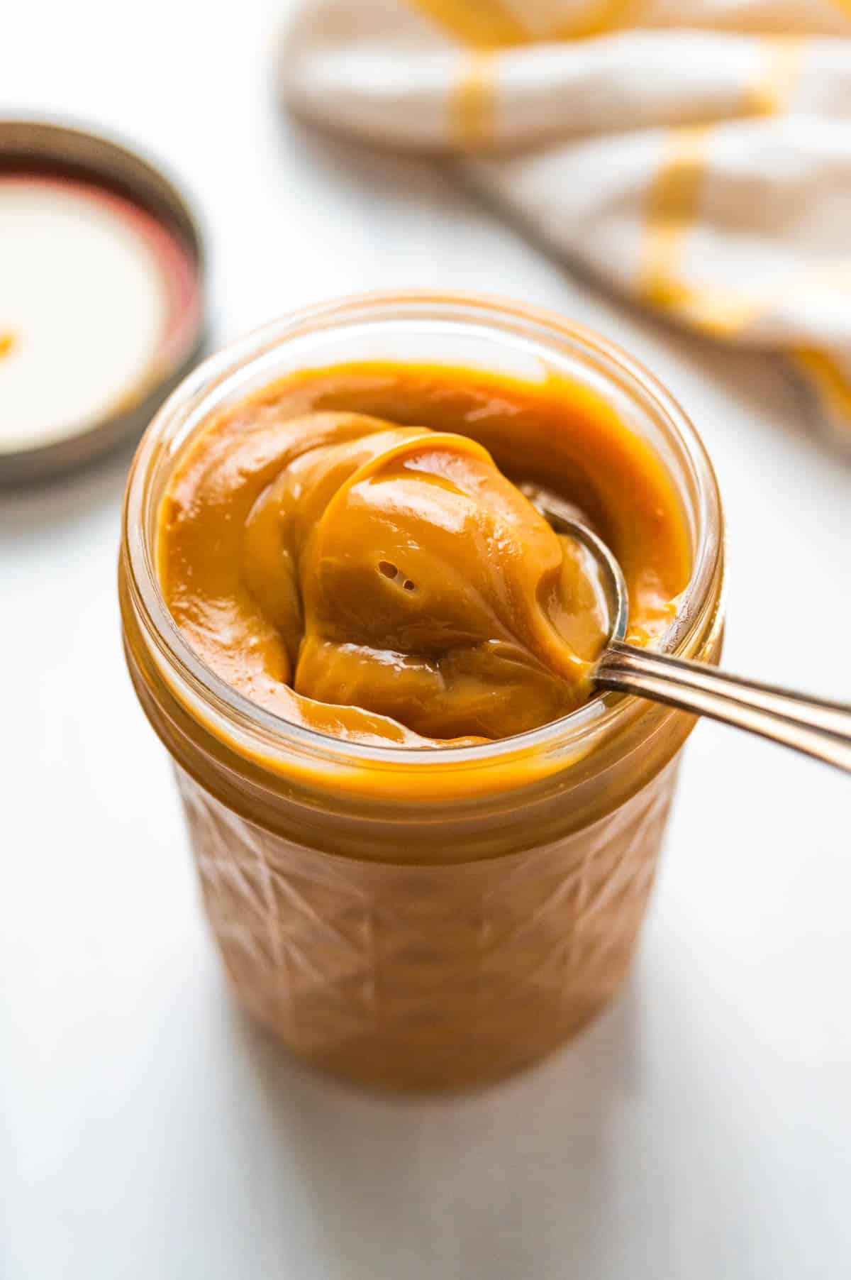 A jar of the dulce de leche with a spoon dipped in.