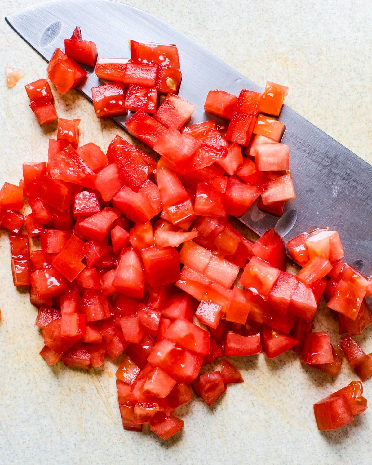 Dicing tomatoes on a cutting board.