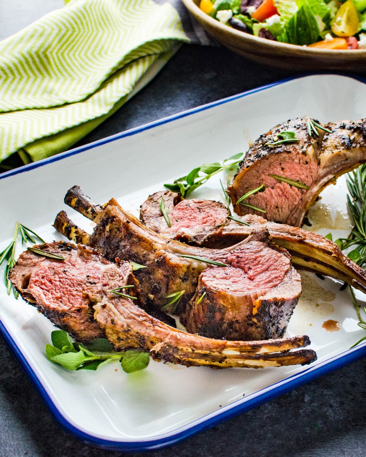 A rimmed platter piled with grilled lamb chops.
