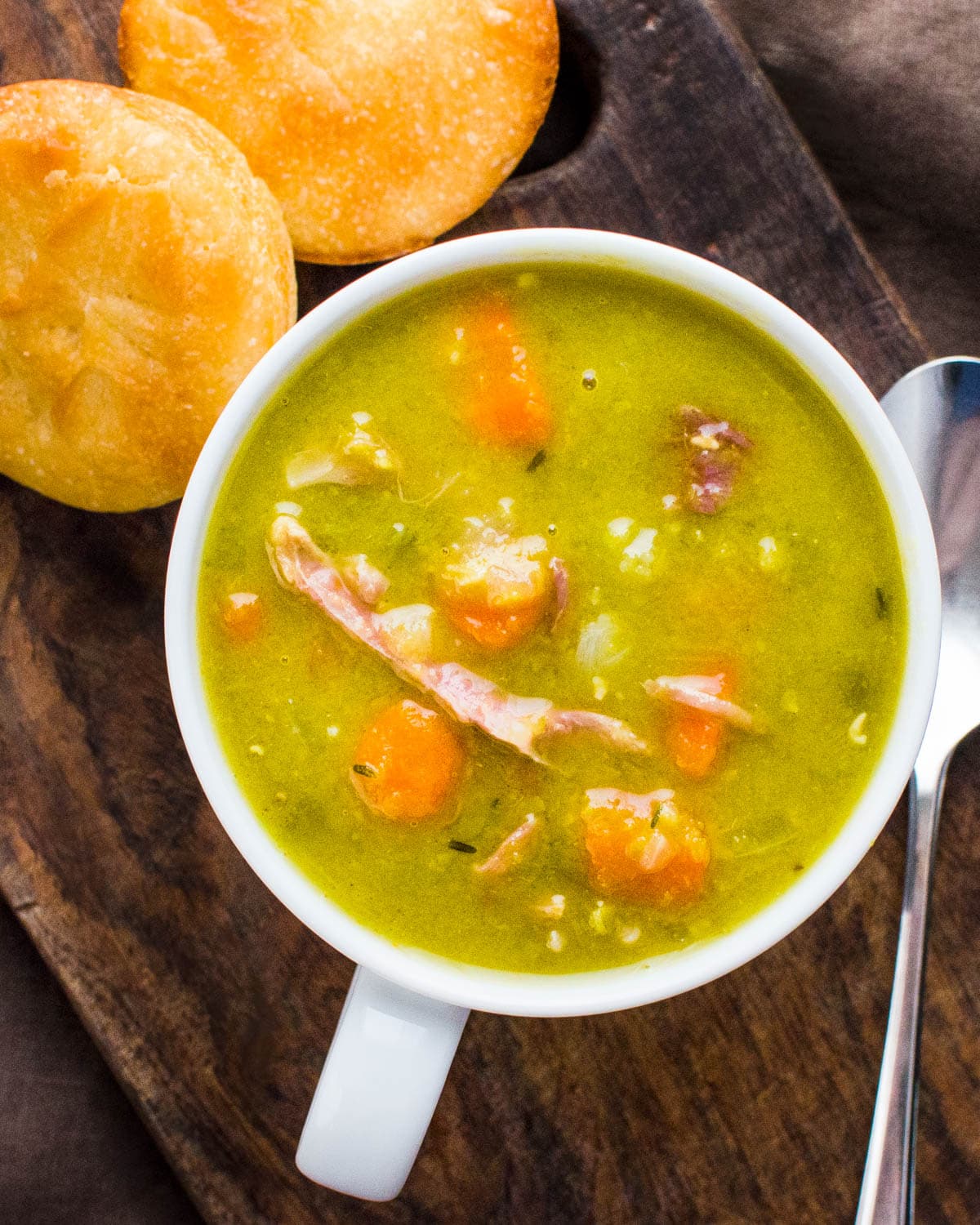 A cup of split pea soup with ham and vegetables.