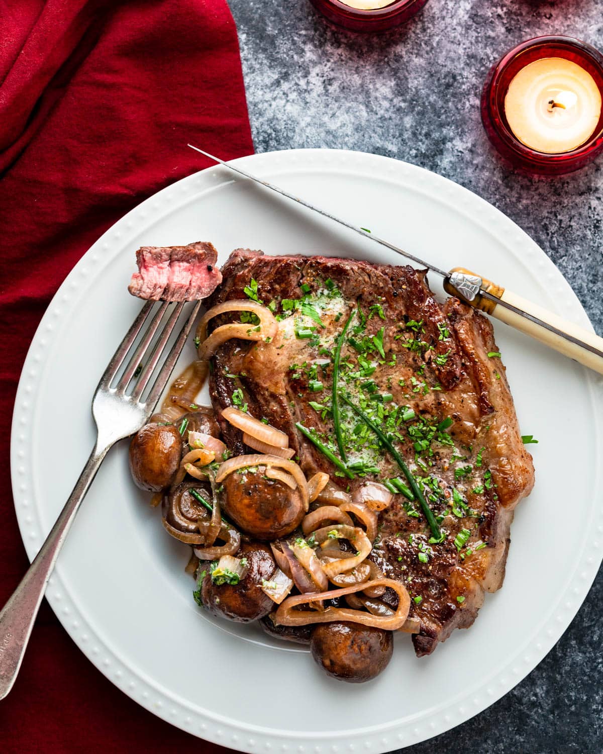 A perfectly cooked steak with mushrooms and onions on a plate.
