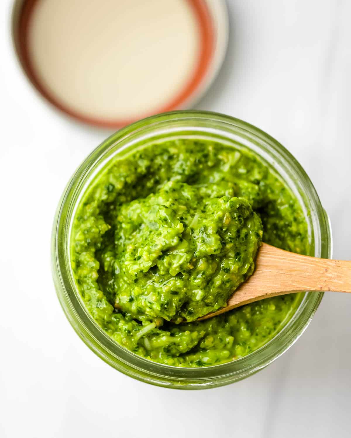 Scooping out the spinach pesto from a jar.