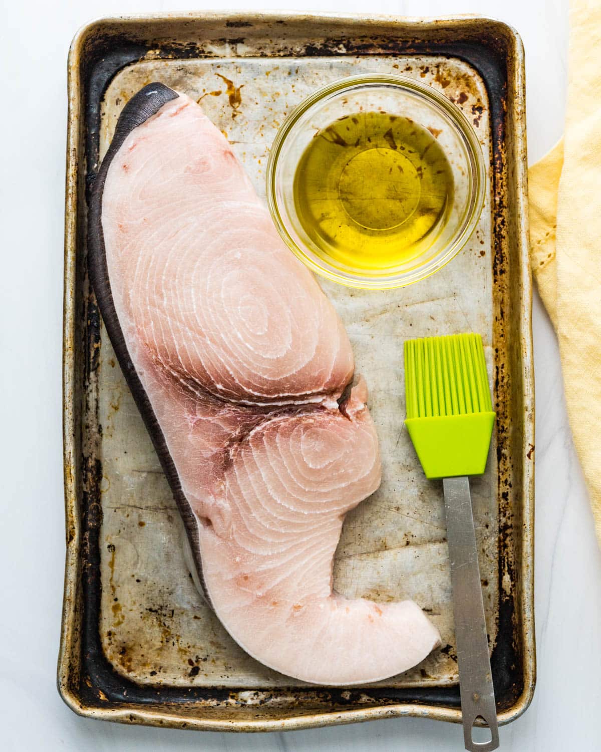 A large swordfish steak on a platter with olive oil.