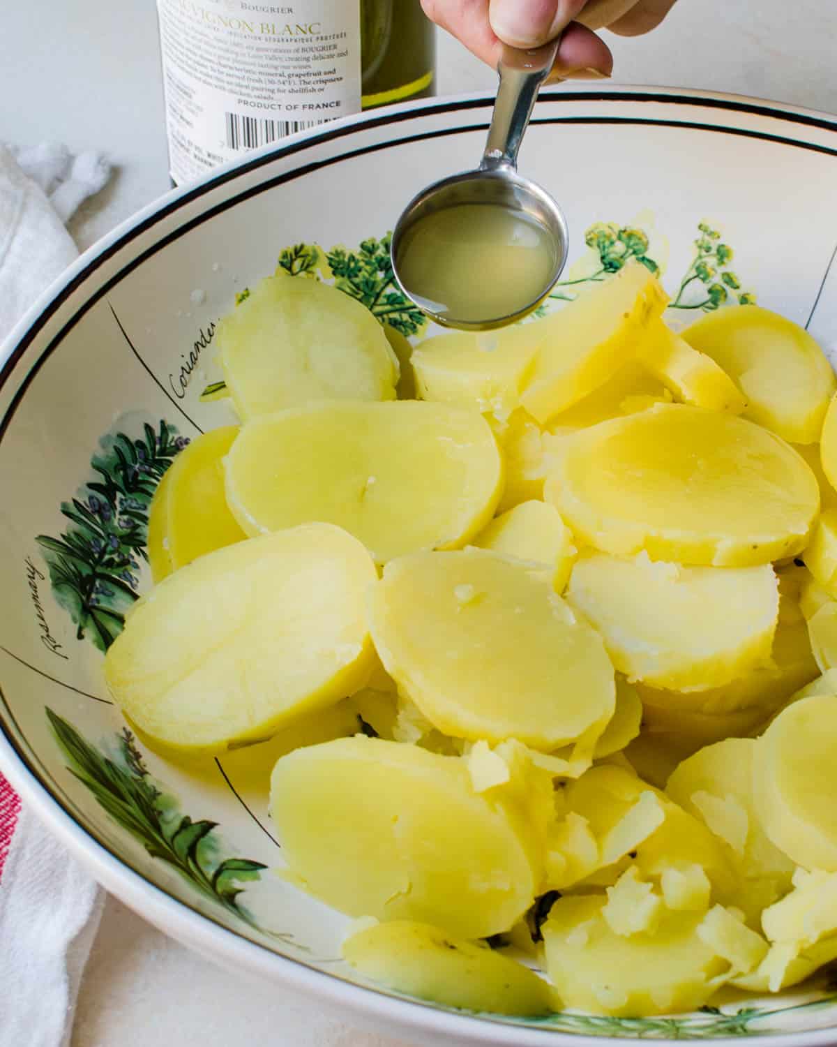 Dressing the hot potatoes with wine and chicken broth.