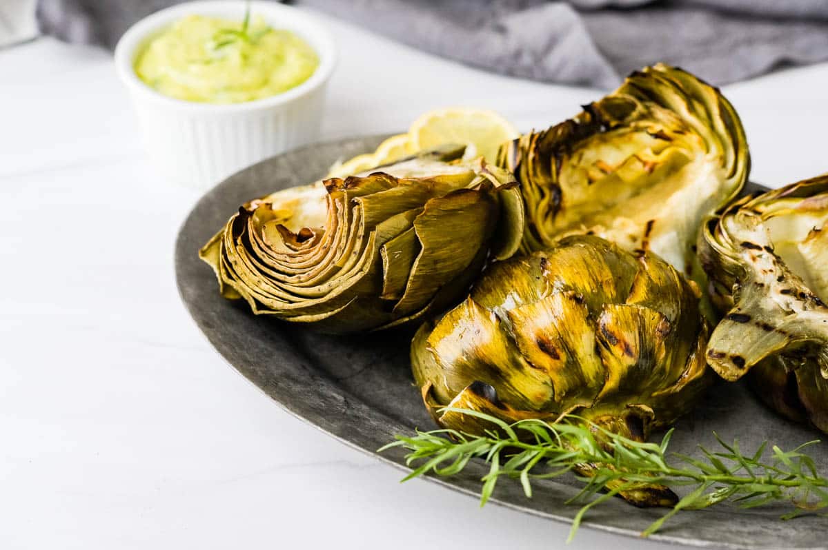 serving the grilled artichokes on a platter with aioli.