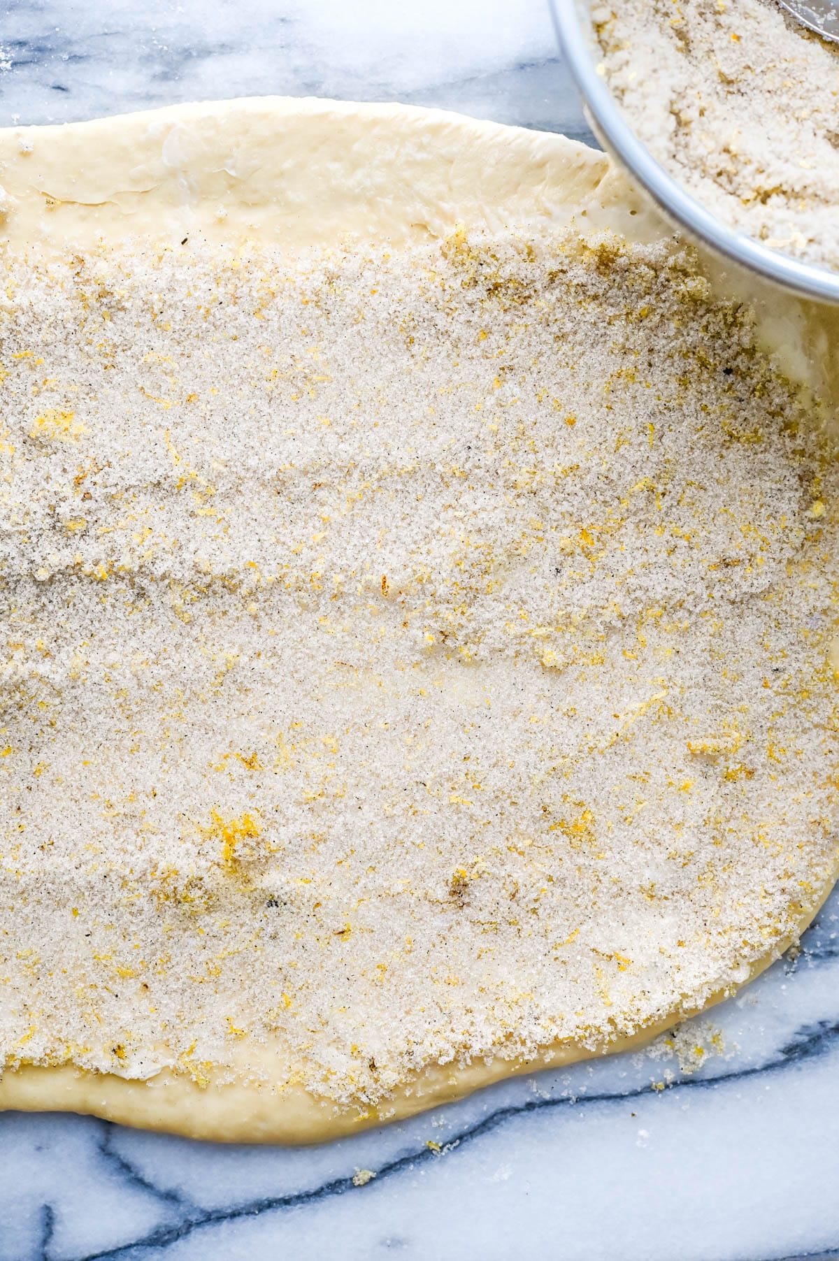 Topping the dough with the lemon sugar filling.