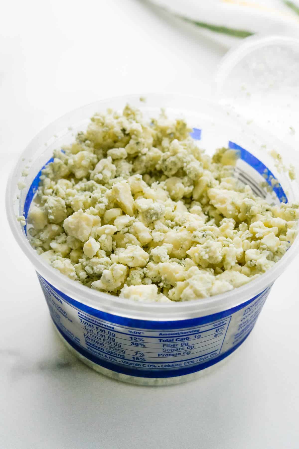 A container of blue cheese crumbles. 