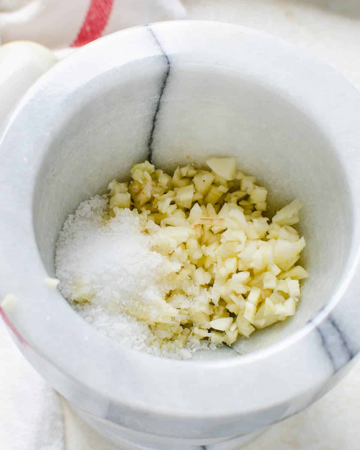 Grinding garlic and kosher salt in a mortar and pestle.