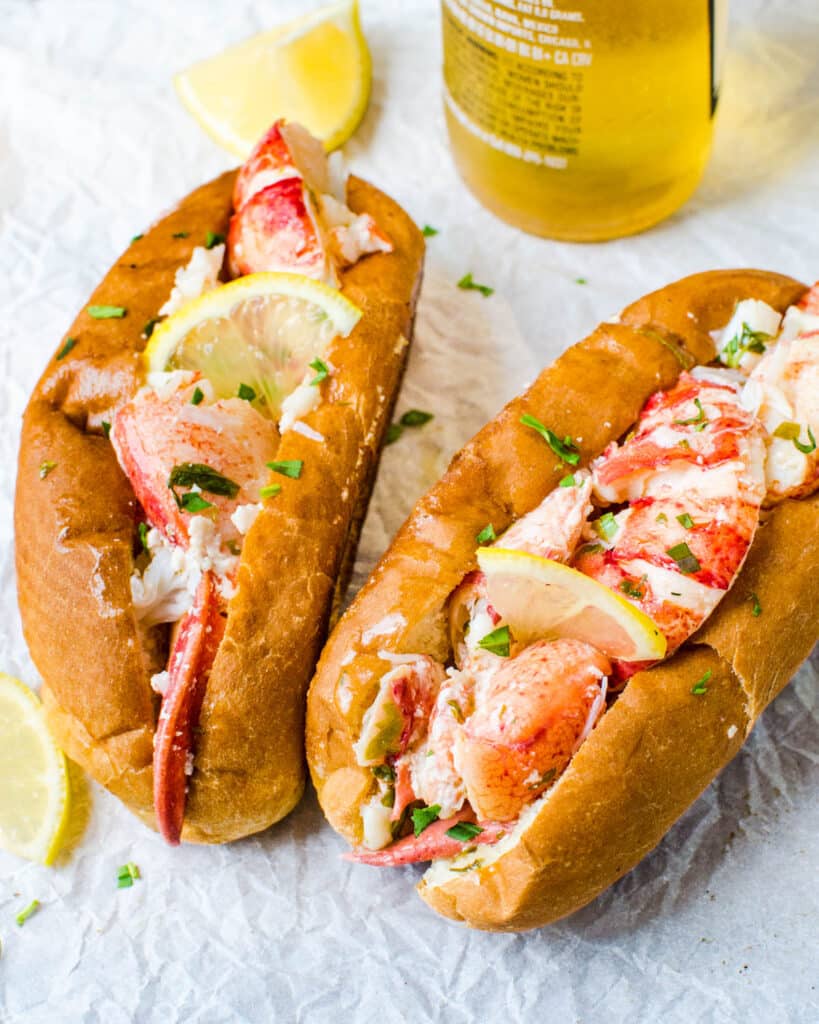 Two Connecticut style lobster rolls in griddled buns with a beer.