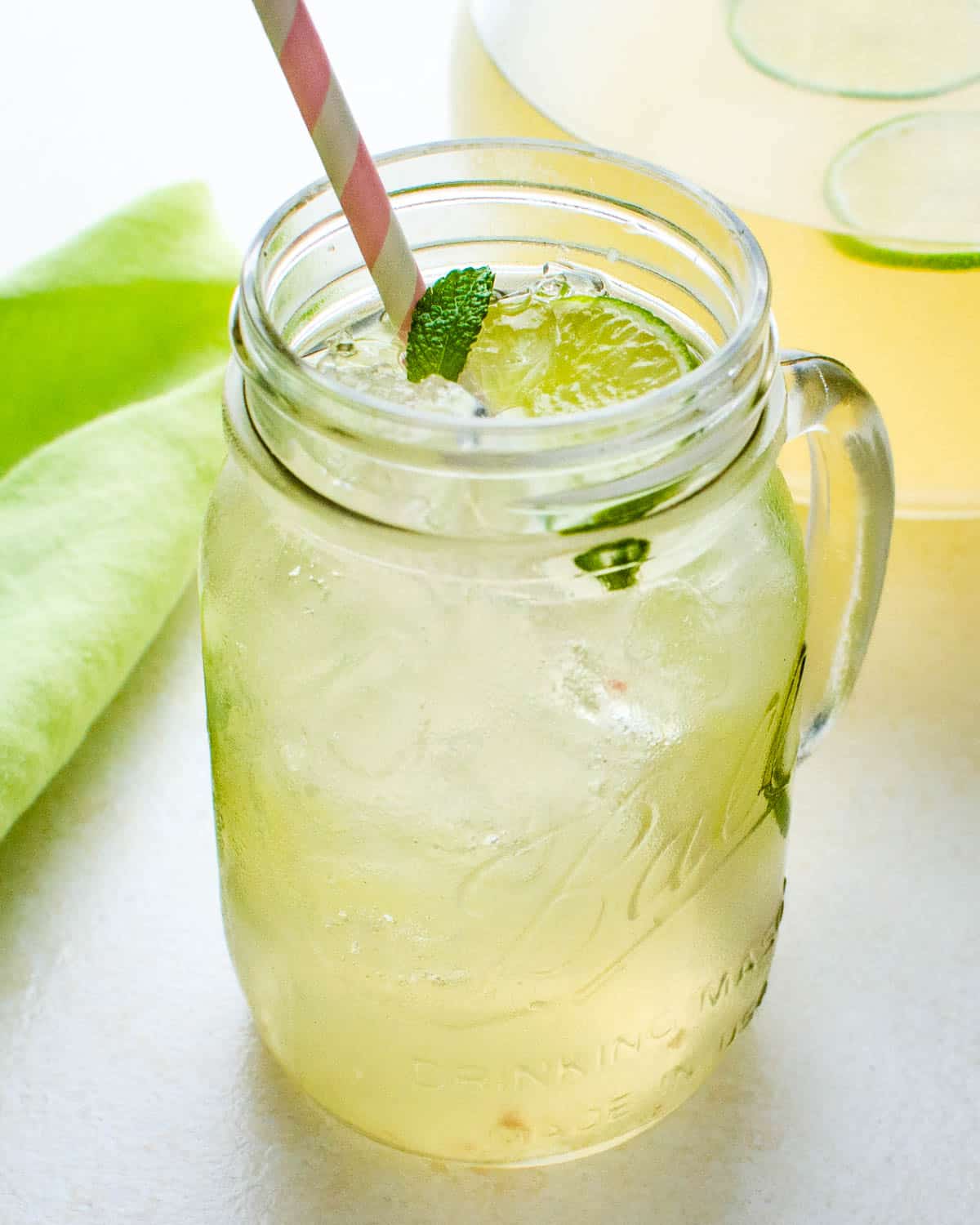 A mason jar filled with ice and guava limeade with mint leaves for garnish.