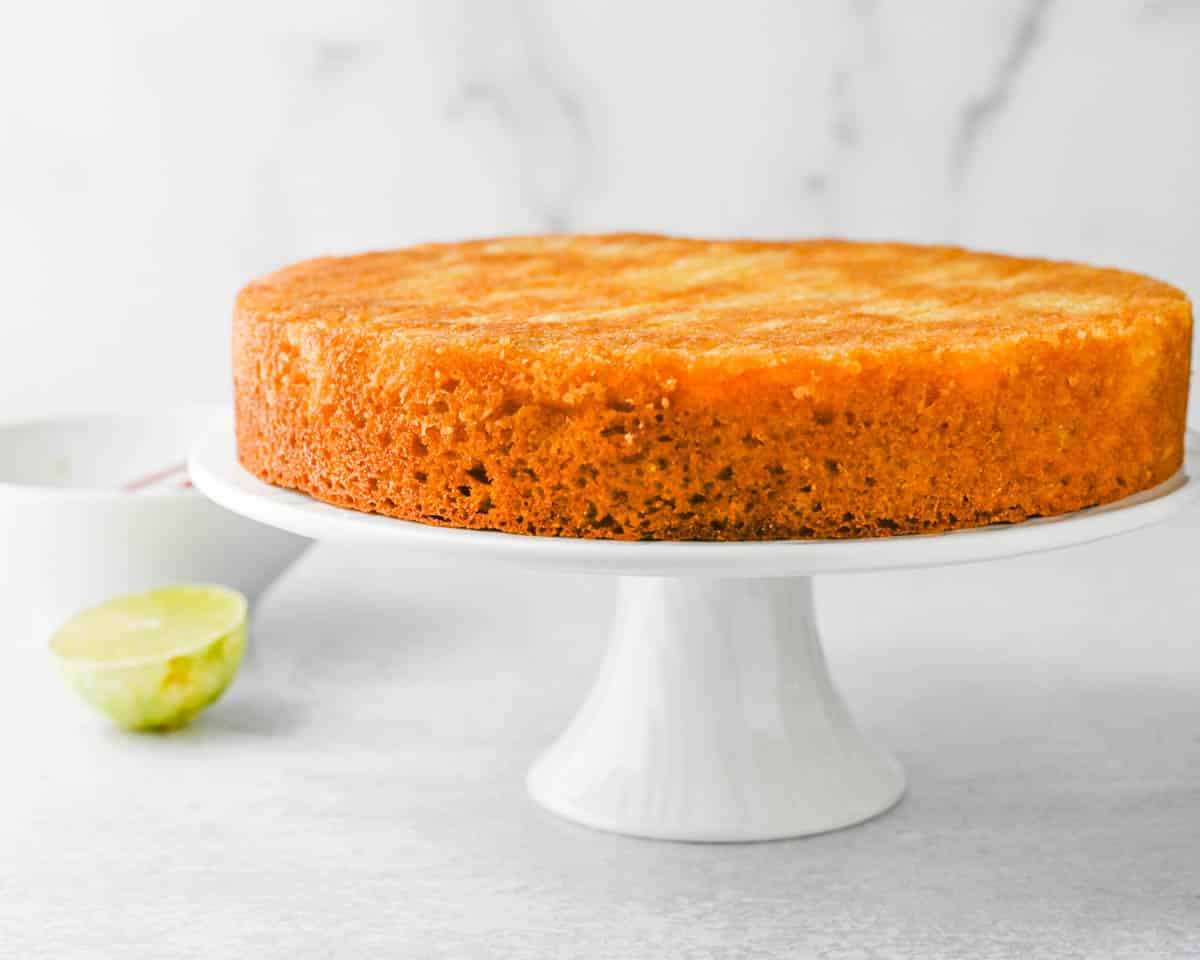 A whole mango cake on a cake pedestal.